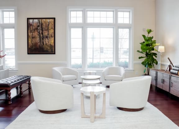 a living room with white furniture and a large window at Broadlands Apartments in Ashburn, Virginia